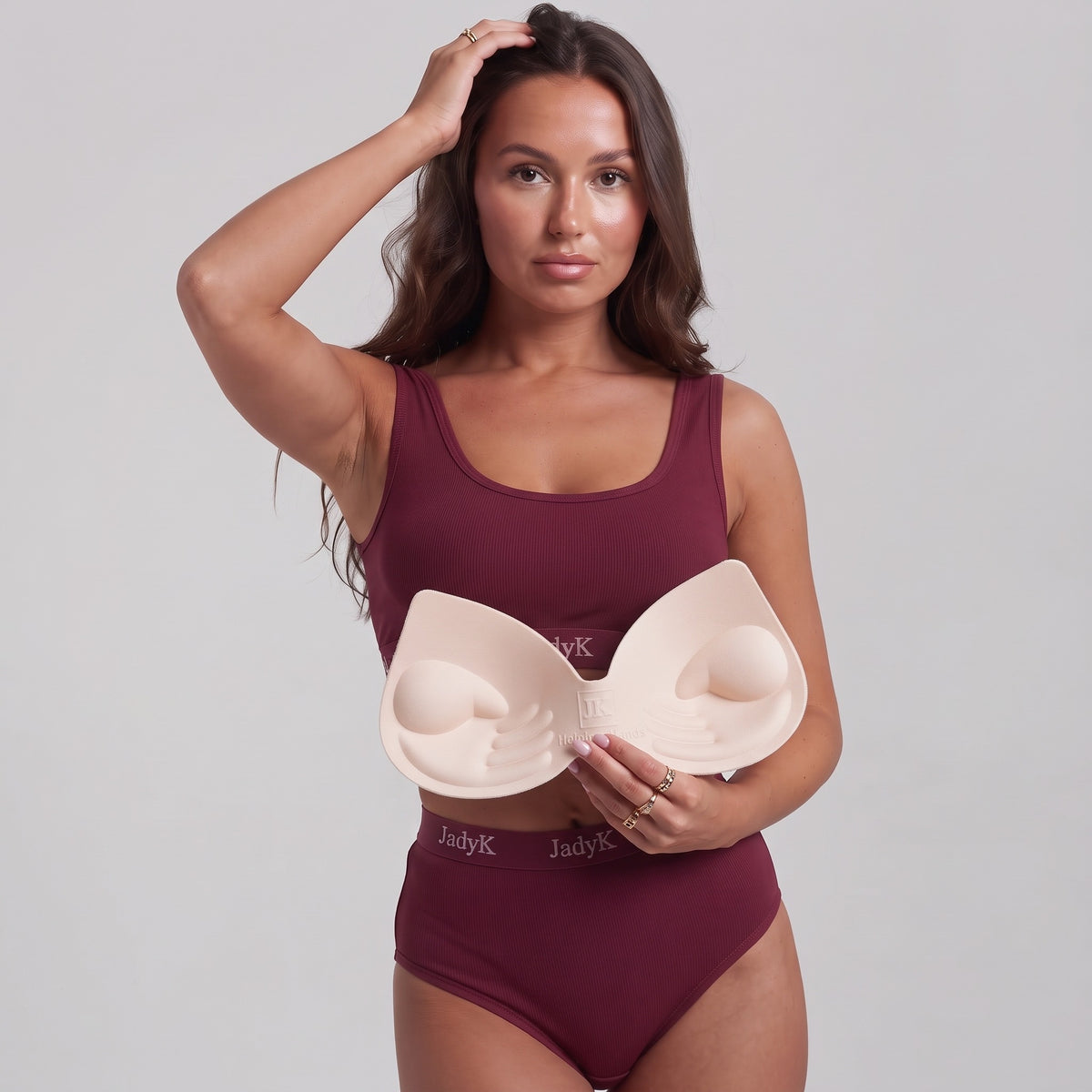Model in burgundy Arya set holding the connected Helping Hands padding